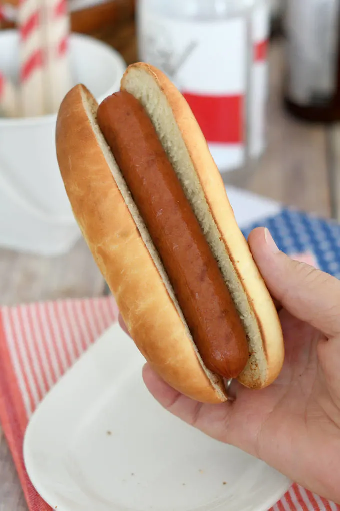 a hand holding a hot dog in a homemade bun