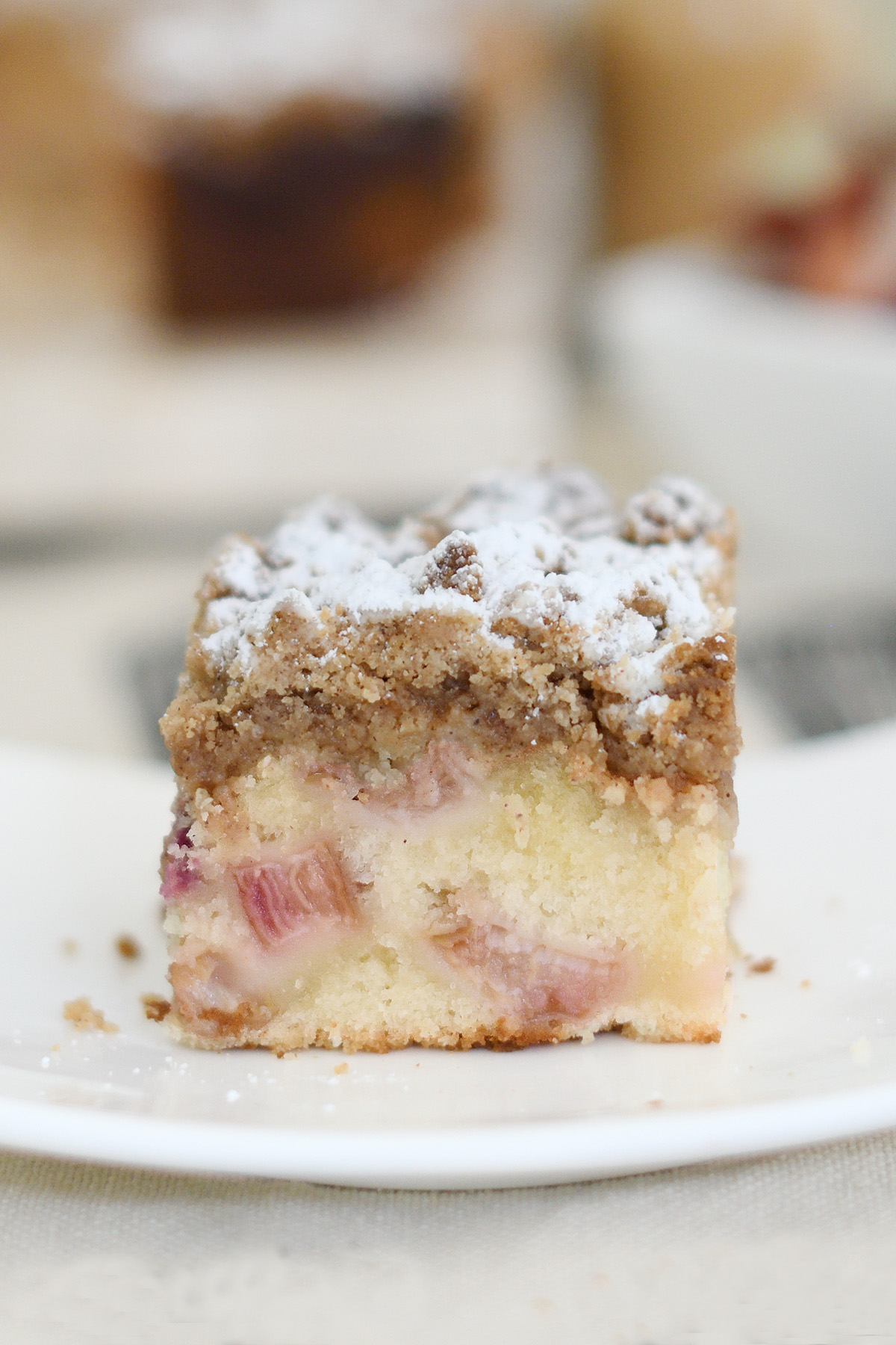 a slice of rhubarb crumb cake on a white plate.