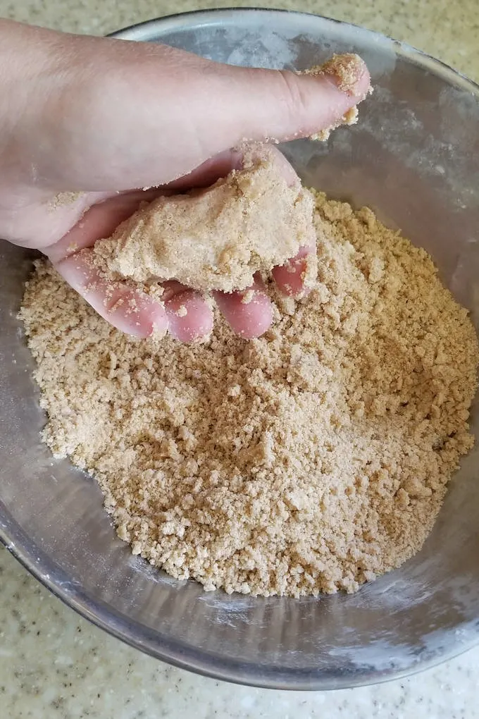 a hand grabbing a clump of brown sugar cake topping