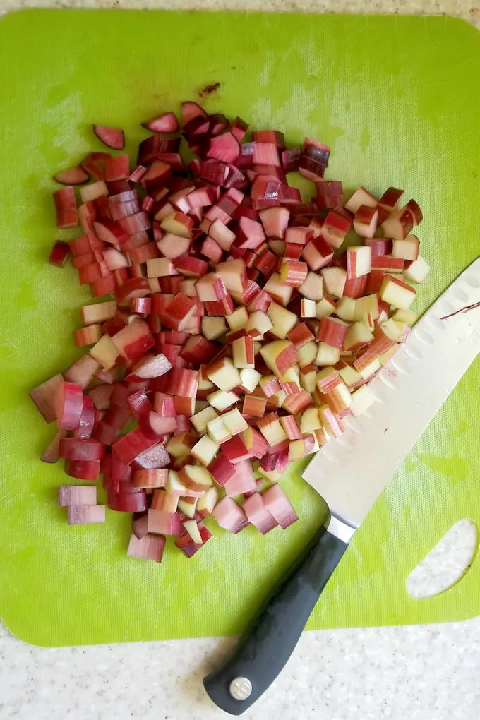 chopped rhubarb on a green cutting board with a knife