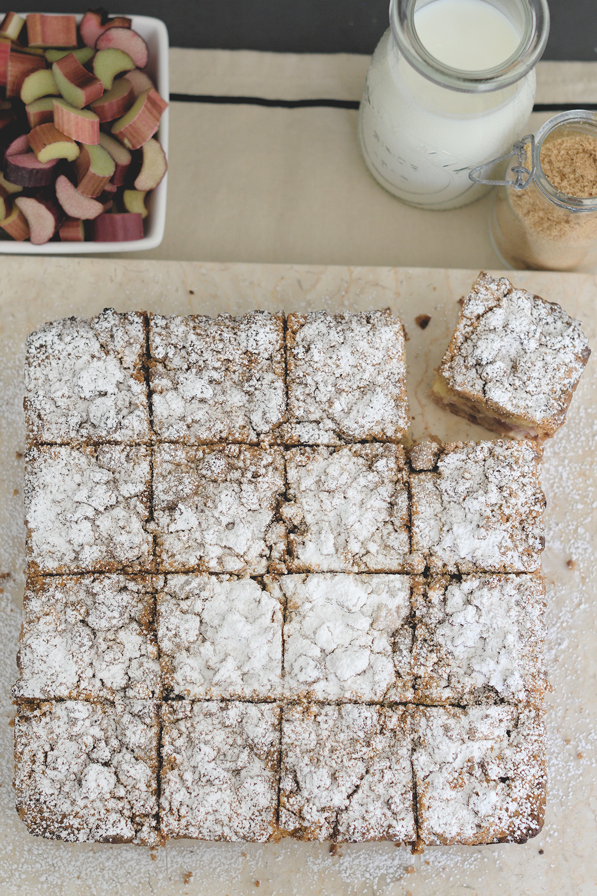 an overhead view of a rhubarb crumb cake with milk in a bottle.