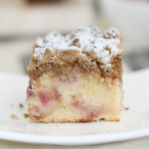 a slice of rhubarb crumb cake on a white plate.