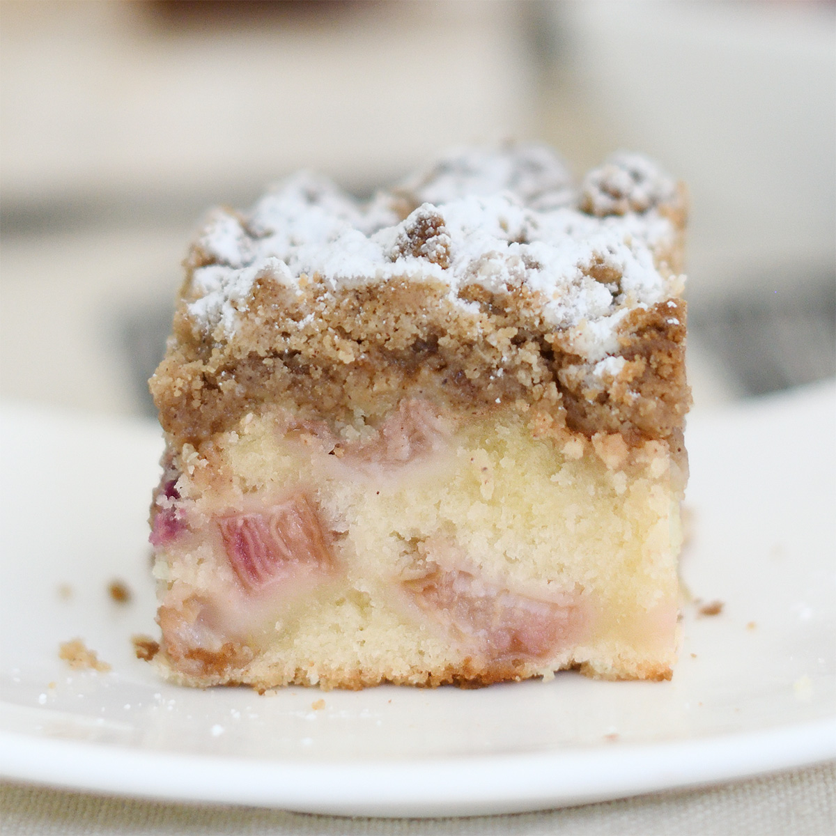 a slice of rhubarb crumb cake on a white plate.
