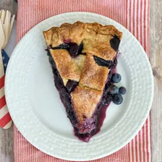 an overheat view of a slice of blueberry pie on a white plate