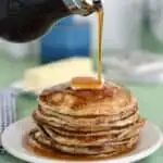 a stack of pancakes with syrup pouring over the stack