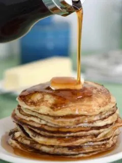 a stack of pancakes with syrup pouring over the stack