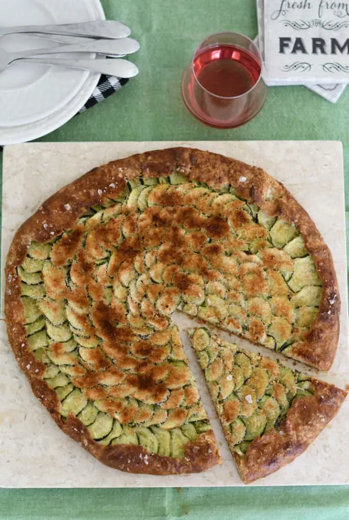 an overhead view of a zucchini galette on a cutting board with a slice cut