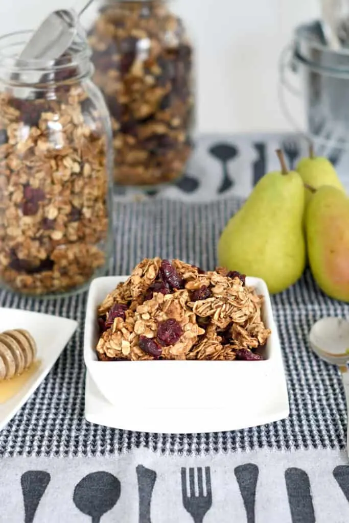 a bowl of chunky granola with a jar of granola in the background