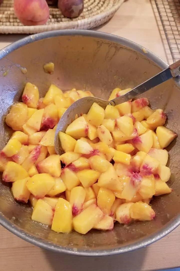a bowl filled with chunks of fresh peaches macerating in sugar