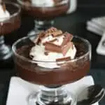 a dish of dark chocolate pudding with whipped cream and chocolate shavings