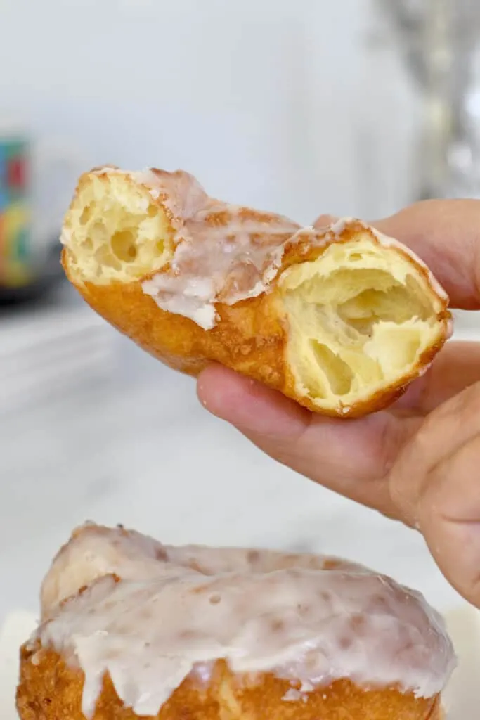 a hand holding half a french cruller