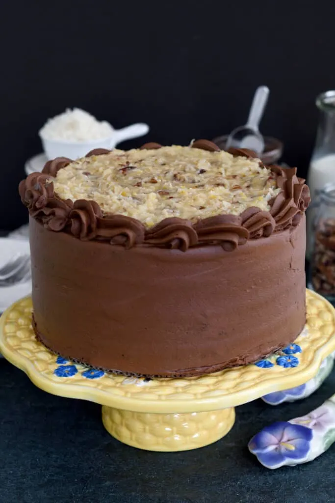 a german chocolate cake on a yellow cake stand, front view