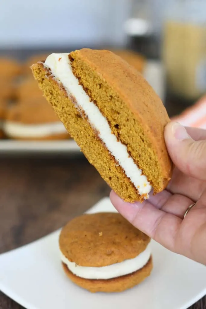 a hand holding a half of a jumbo pumpkin whoopie pie