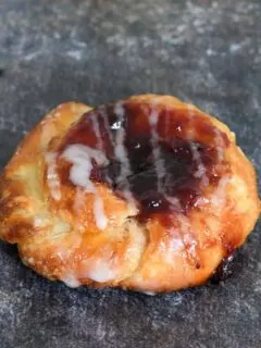 a sourdough danish pastry filled with jam is on a gray background