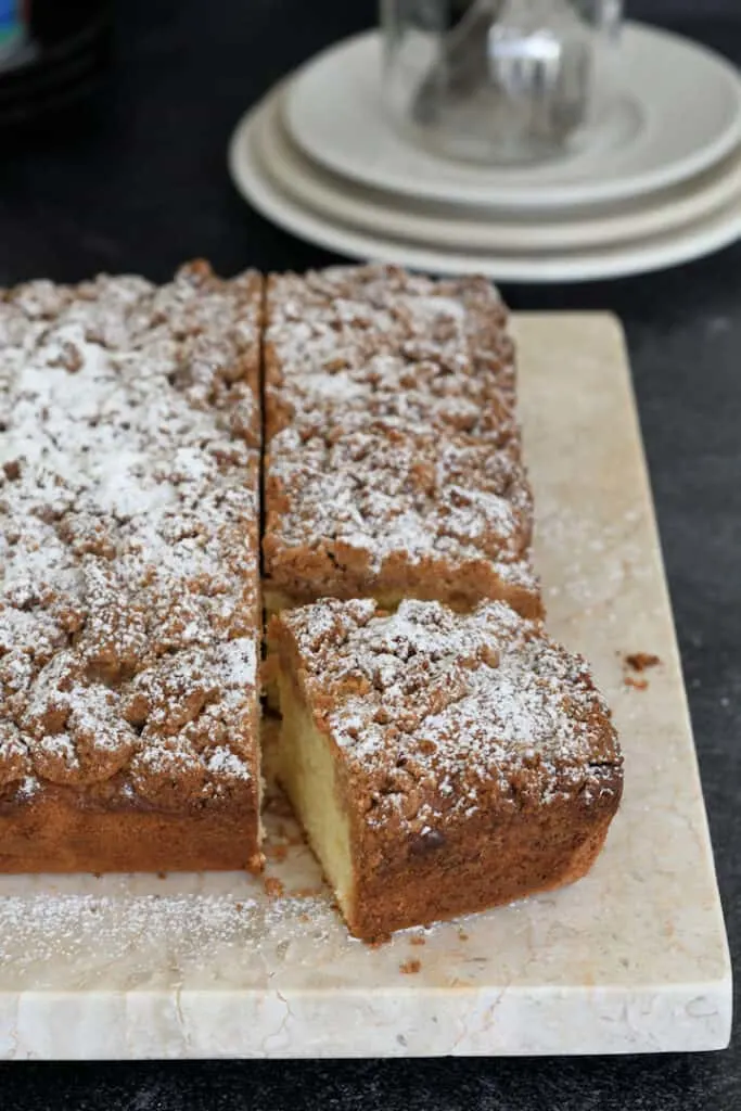 a sourdough discard crumb cake on a cutting board with a slice removed