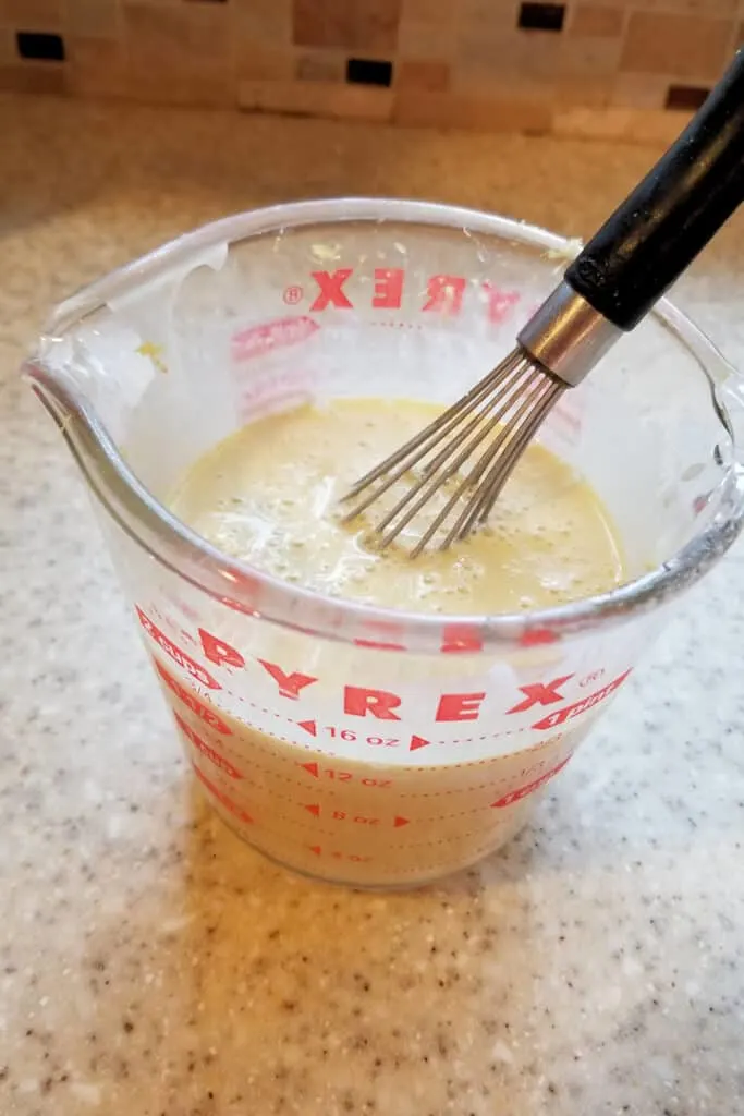 a glass measuring cup filled with sourdough starter, olive oil and eggs.
