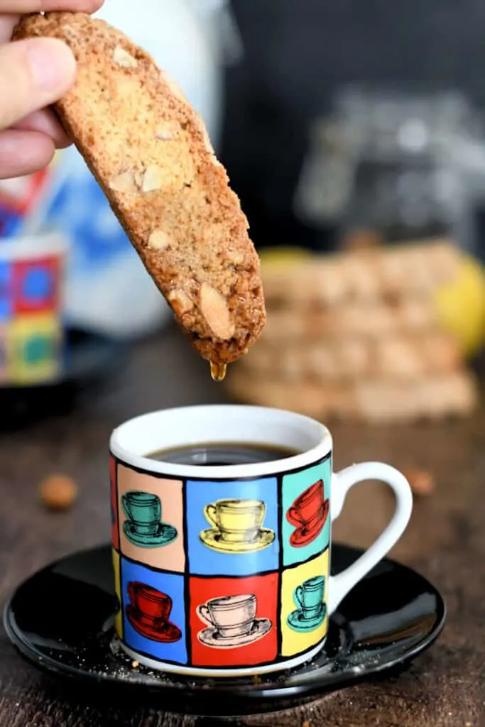 a biscotti being dunked in a cup of expresso
