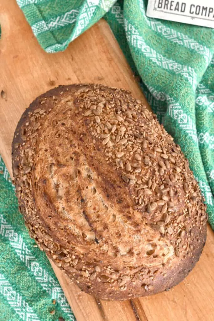 a loaf of sourdough cracked wheat bread on a cutting board