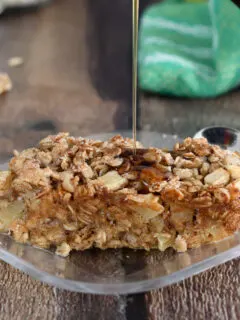 a slice of apple maple baked oatmeal on a plate being drizzled with maple syrup