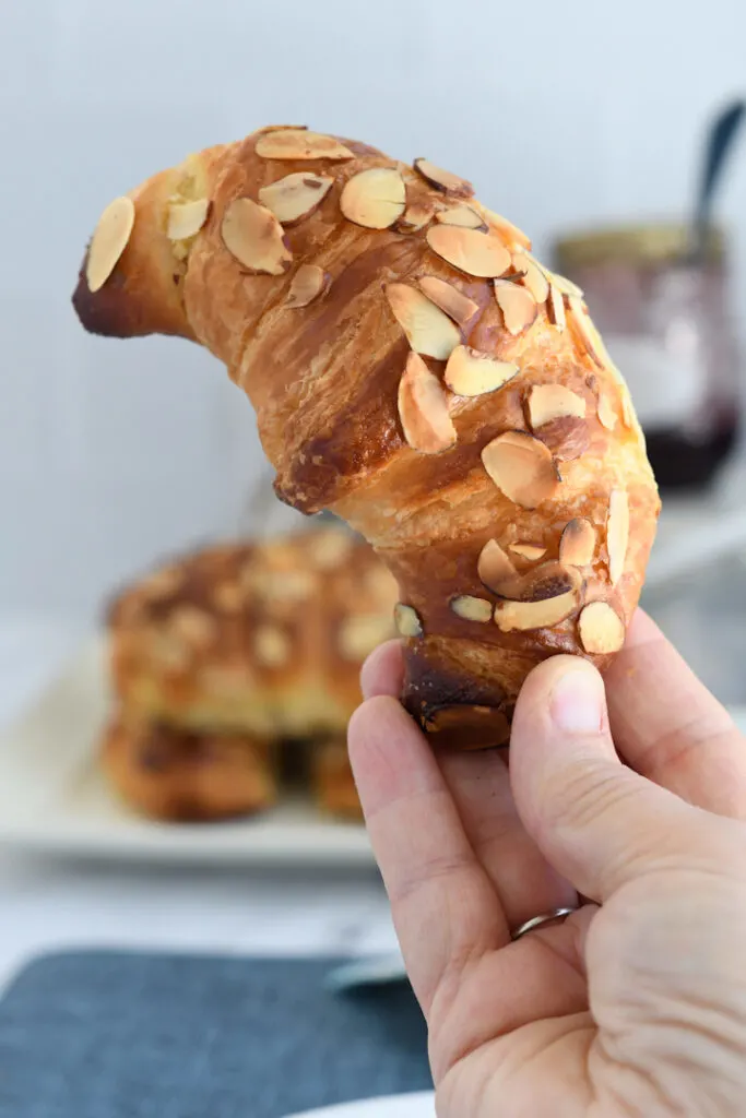 a hand holding an almond croissant