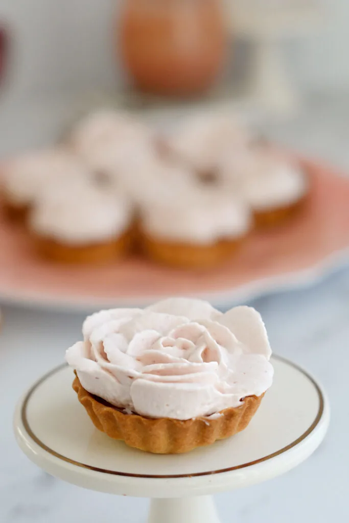 a single raspberry rose tart on a mini cake stand