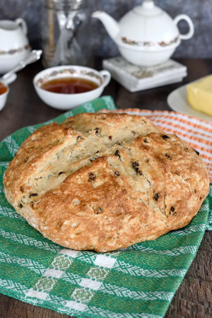 a loaf of sourdough irish soda bread with raisins on a table set for tea