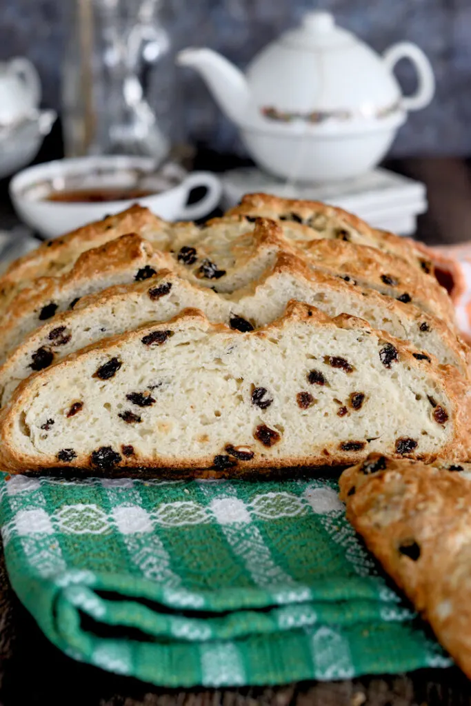 a sliced loaf of soda bread with raising on a green towel