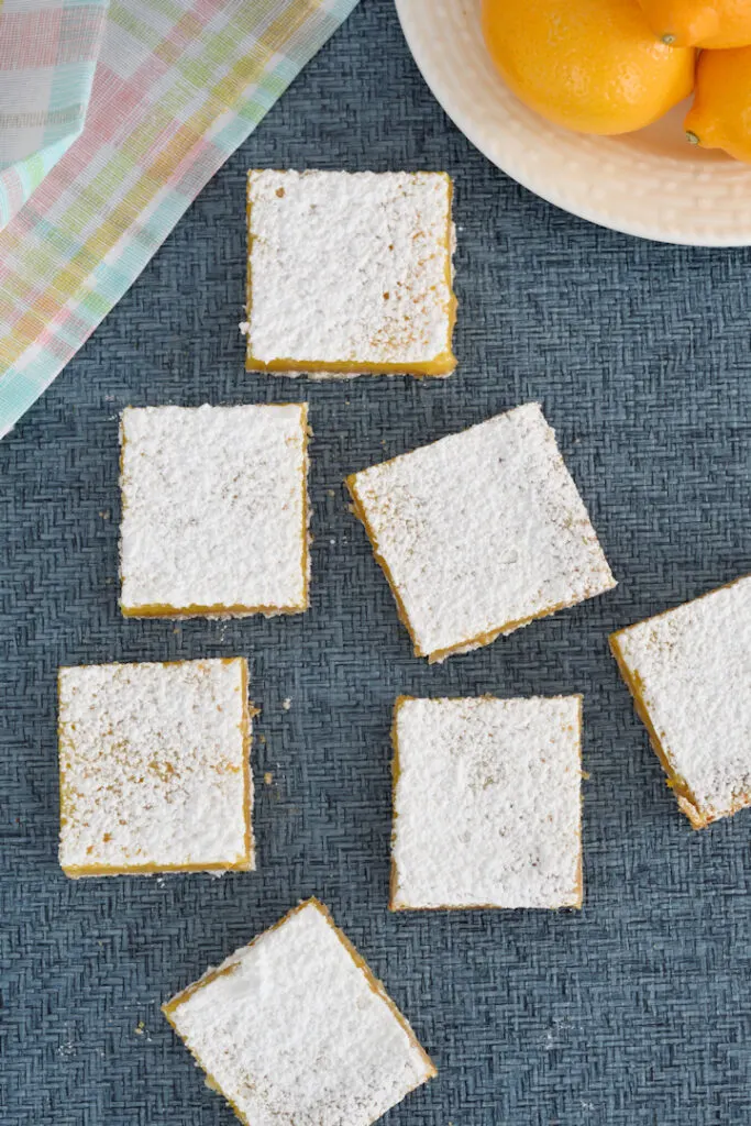 a blue surface with sugar topped meyer lemons bars from overhead