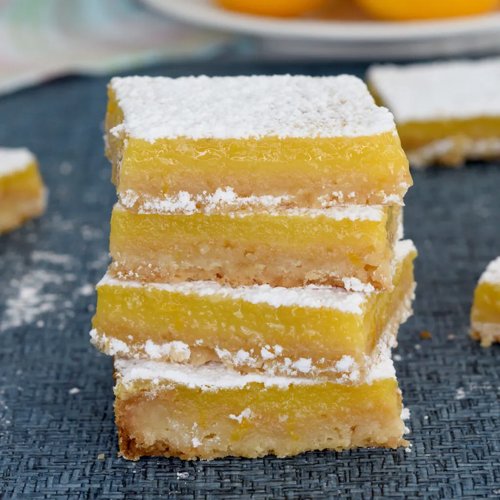 a stack of meyer lemon bars on a blue surface
