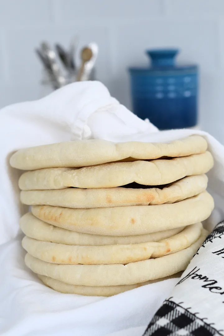 a stack of homemade pita bread wrapped in a towel