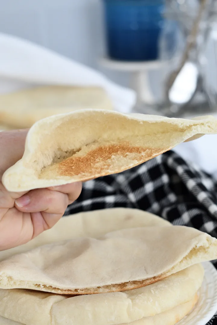 a hand holding half a pita bread showing the open pocket