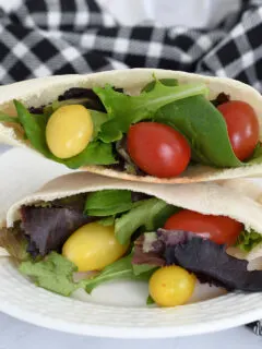 pita bread filled with lettuce and tomatoes on a plate