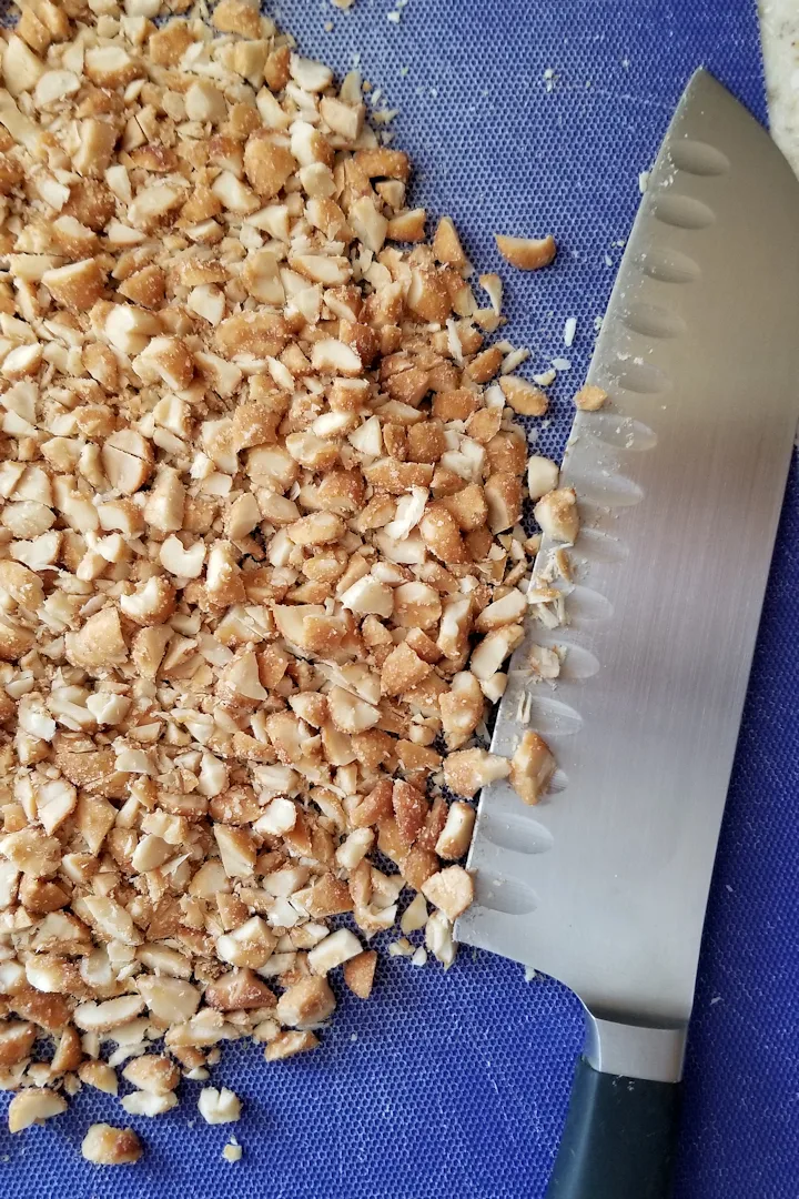 a cutting board with a knife and chopped peanut