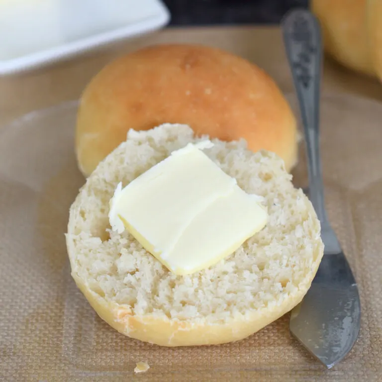 a dinner roll with butter on a plate.