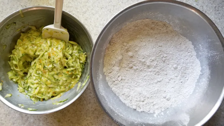 a bowl of zucchini with eggs and another bowl with flour and spices