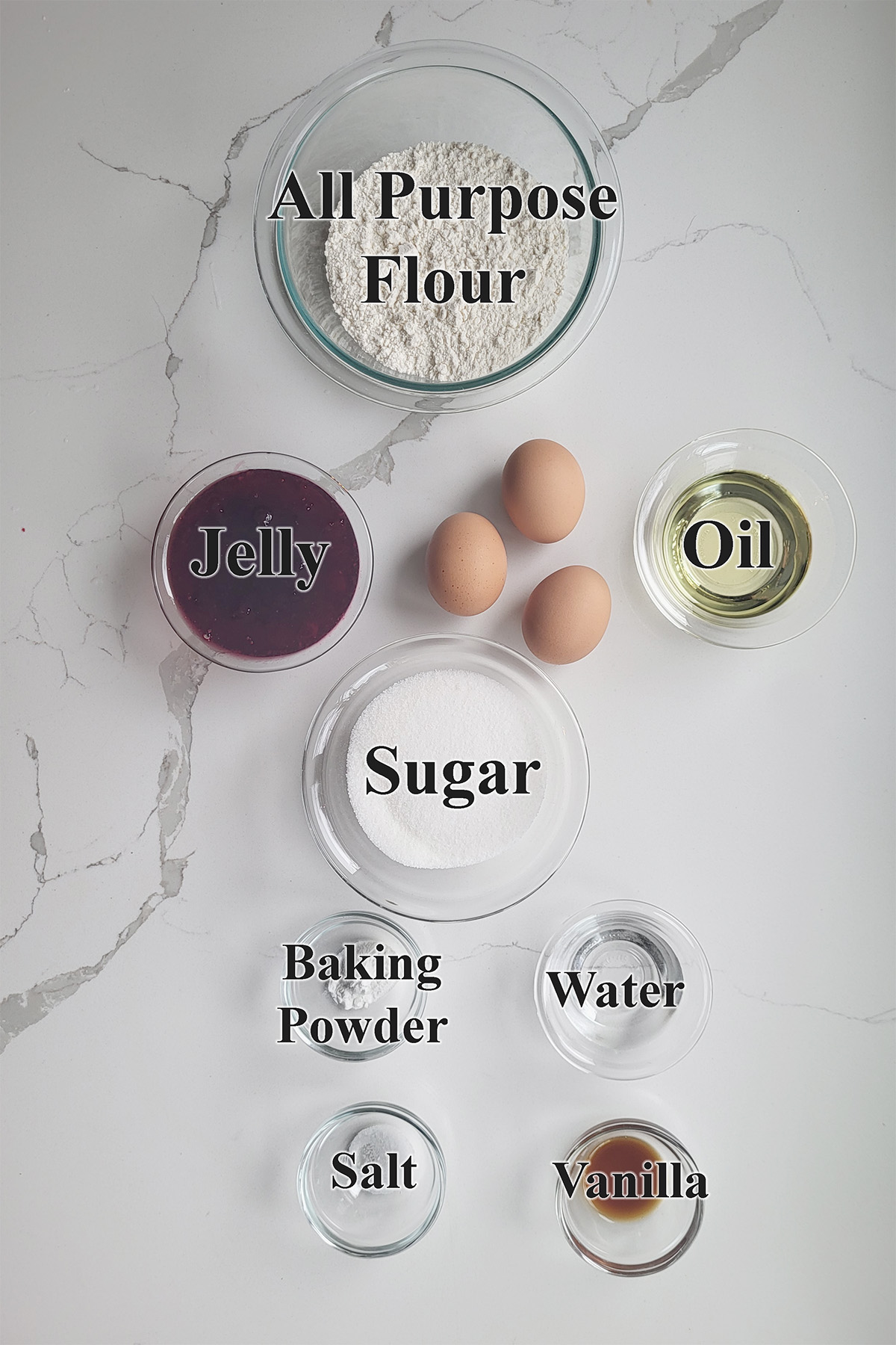 ingredients for jelly roll cake in glass bowls on a white surface.