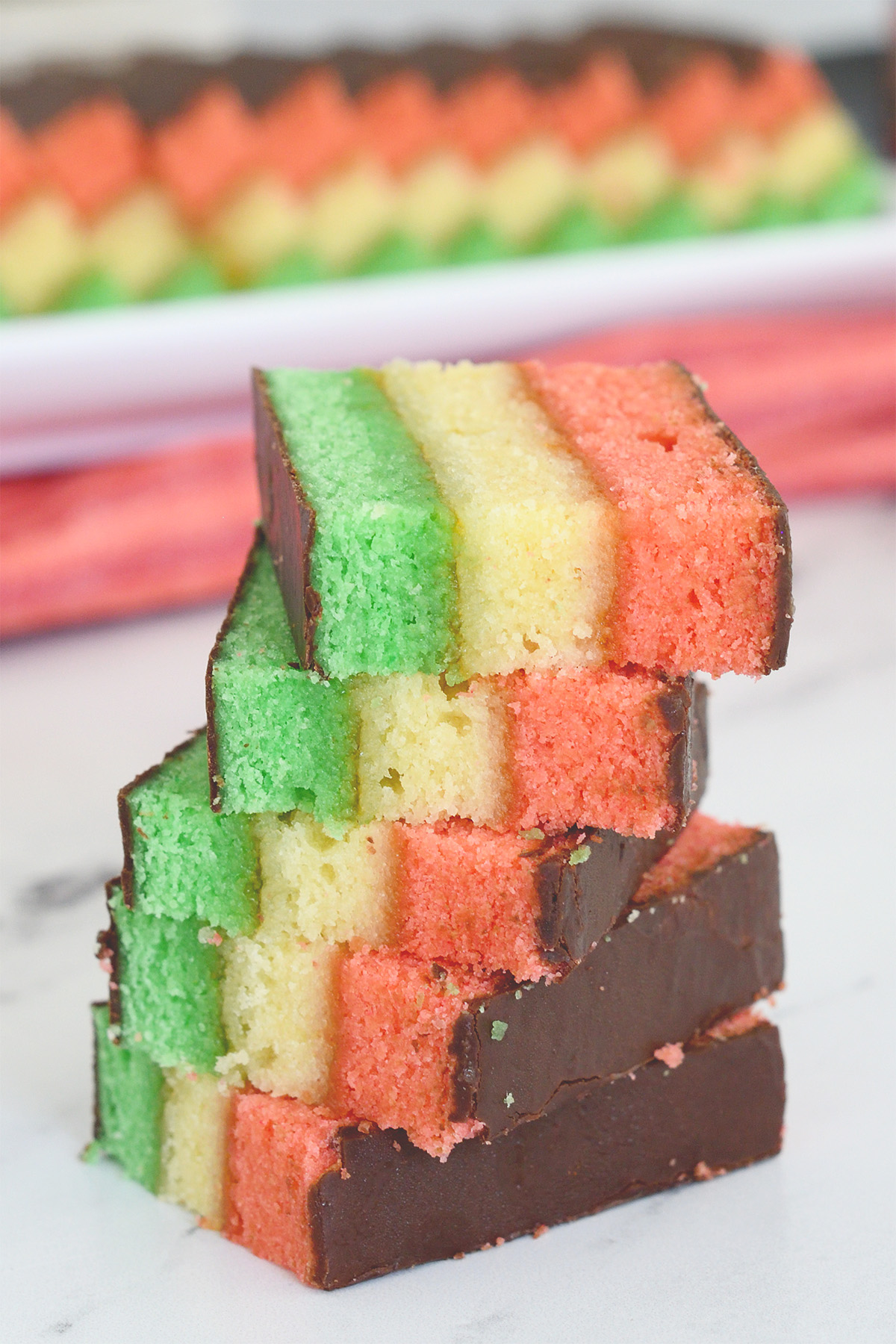 a stack of italian rainbow cookies on a white plate.