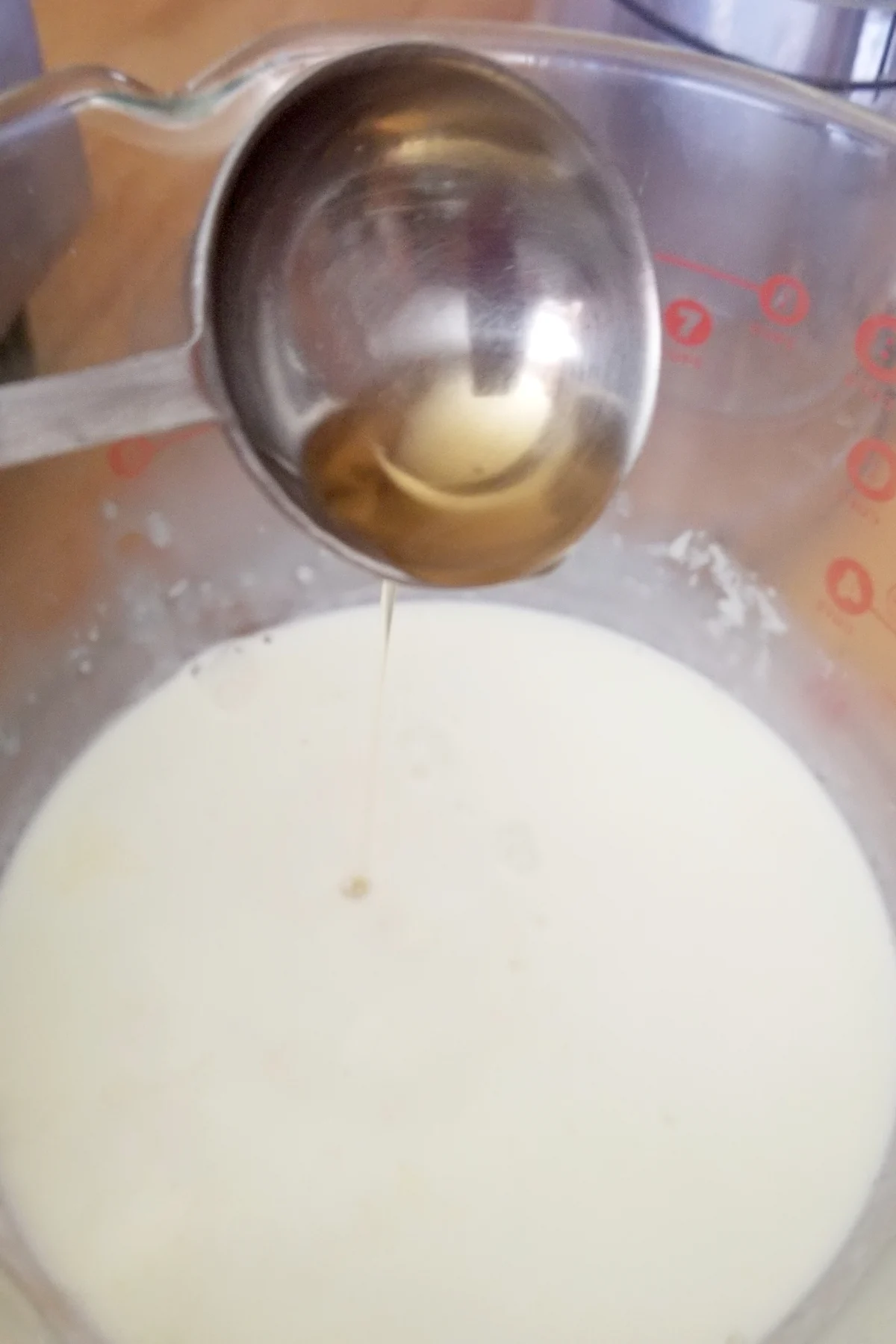 a spoon pouring brandy into a bowl of heavy cream