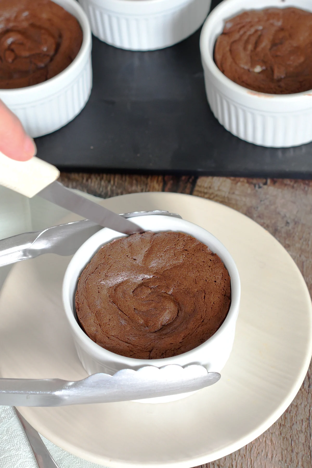 a ramekin with baked cake and a knife going around the sides