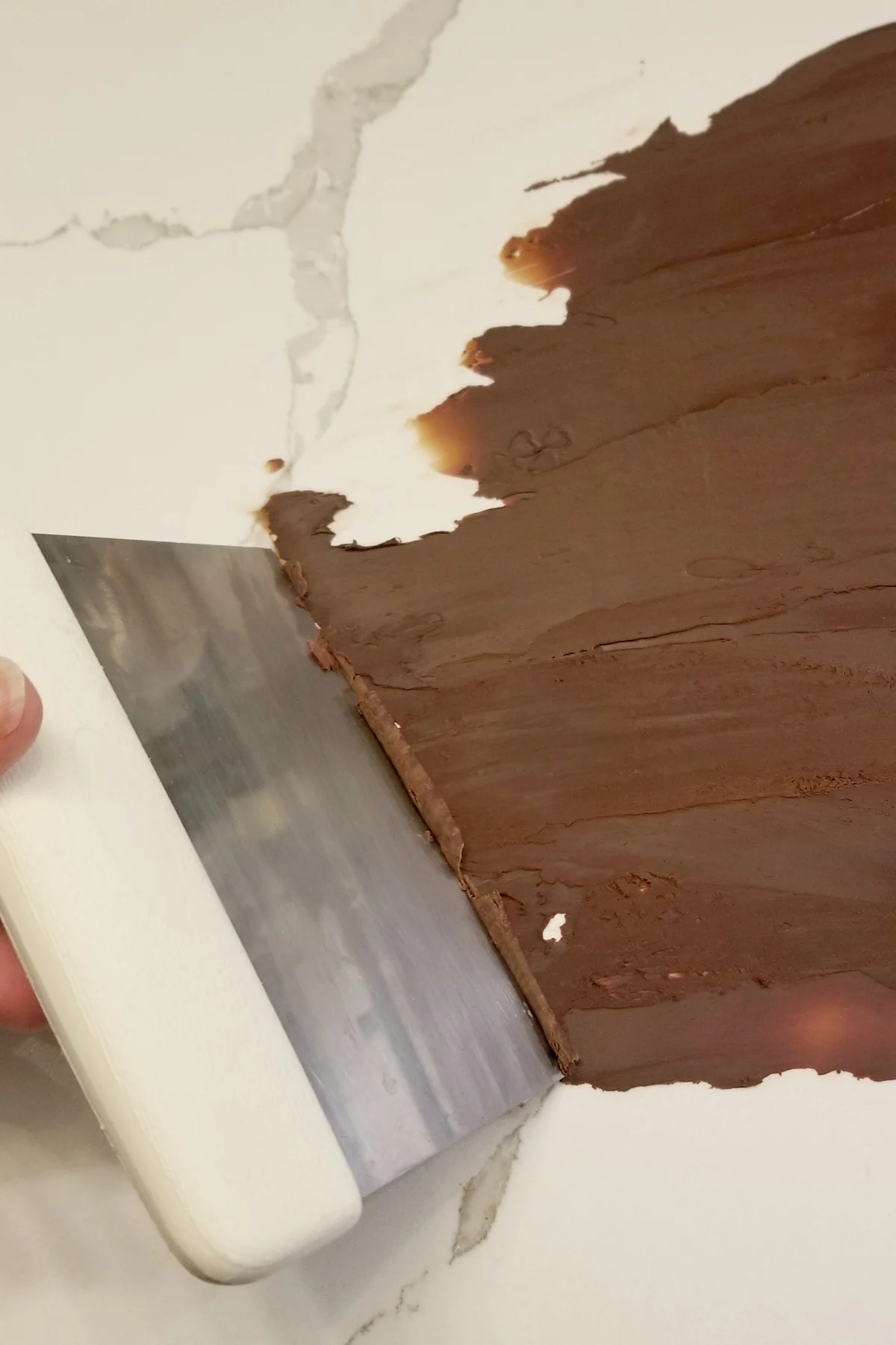 a dough scraper scraping chocolate into curls