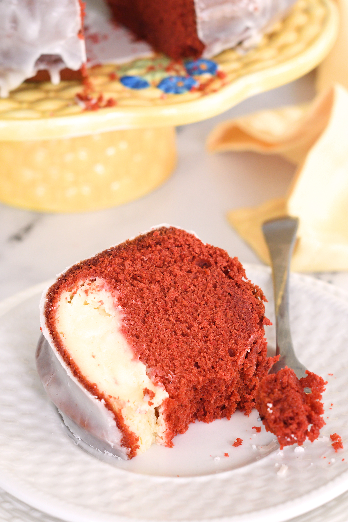 a slice of red velvet cream cheese bundt cake on a white plate.