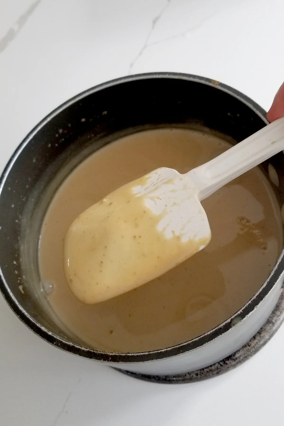 a pot of chai spice custard with a spatula coated in the custard