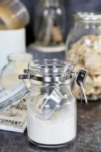 a jar of sourdough powder and a scooper.