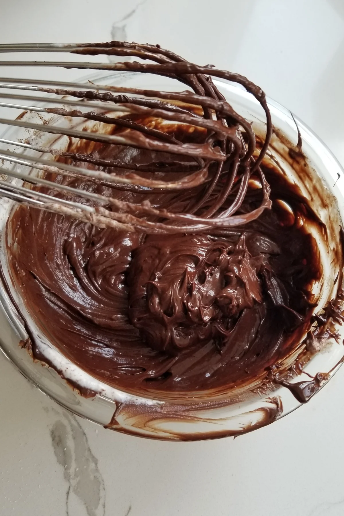 a bowl of dark chocolate cream with a whisk