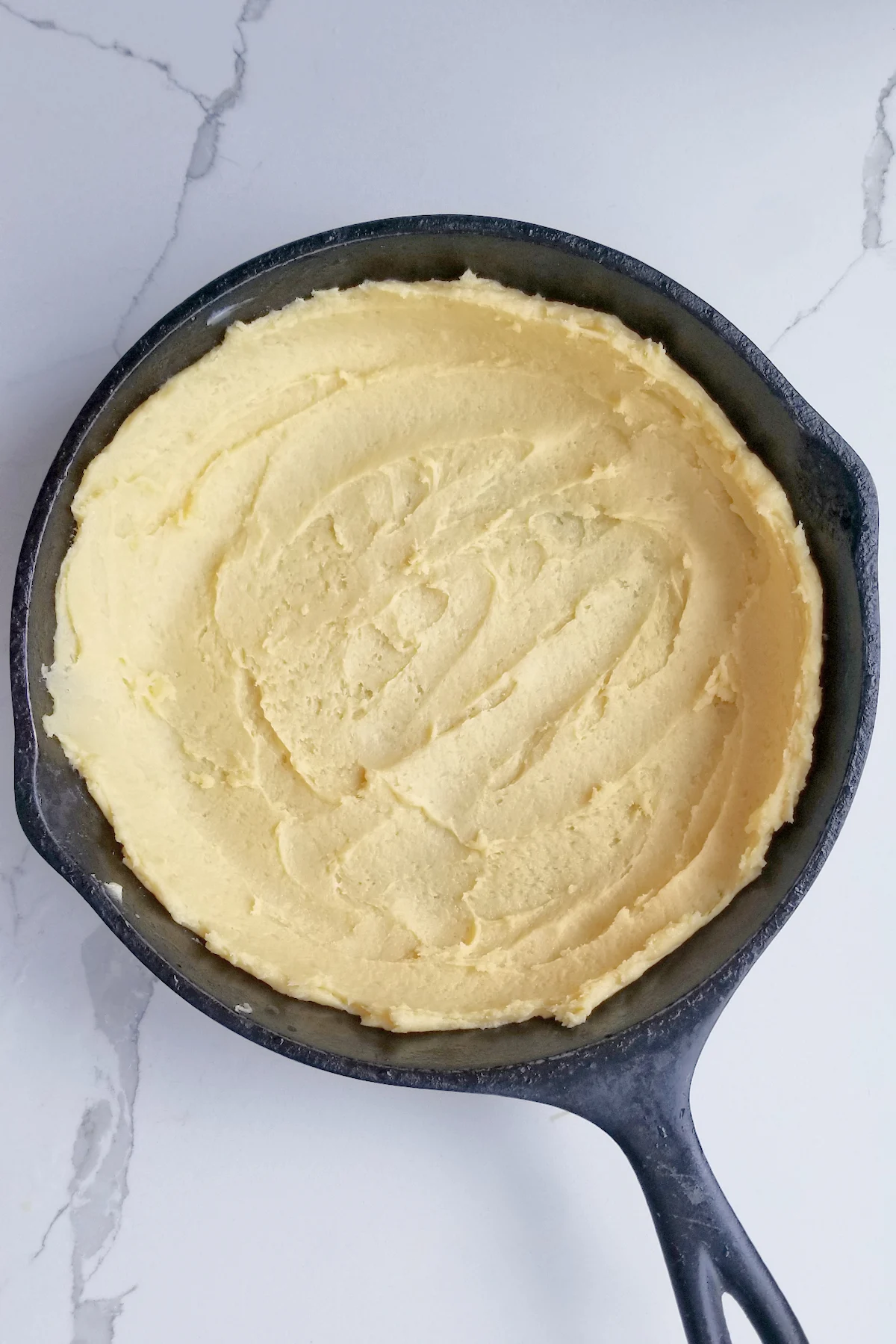 cake batter spread into a cast iron skillet