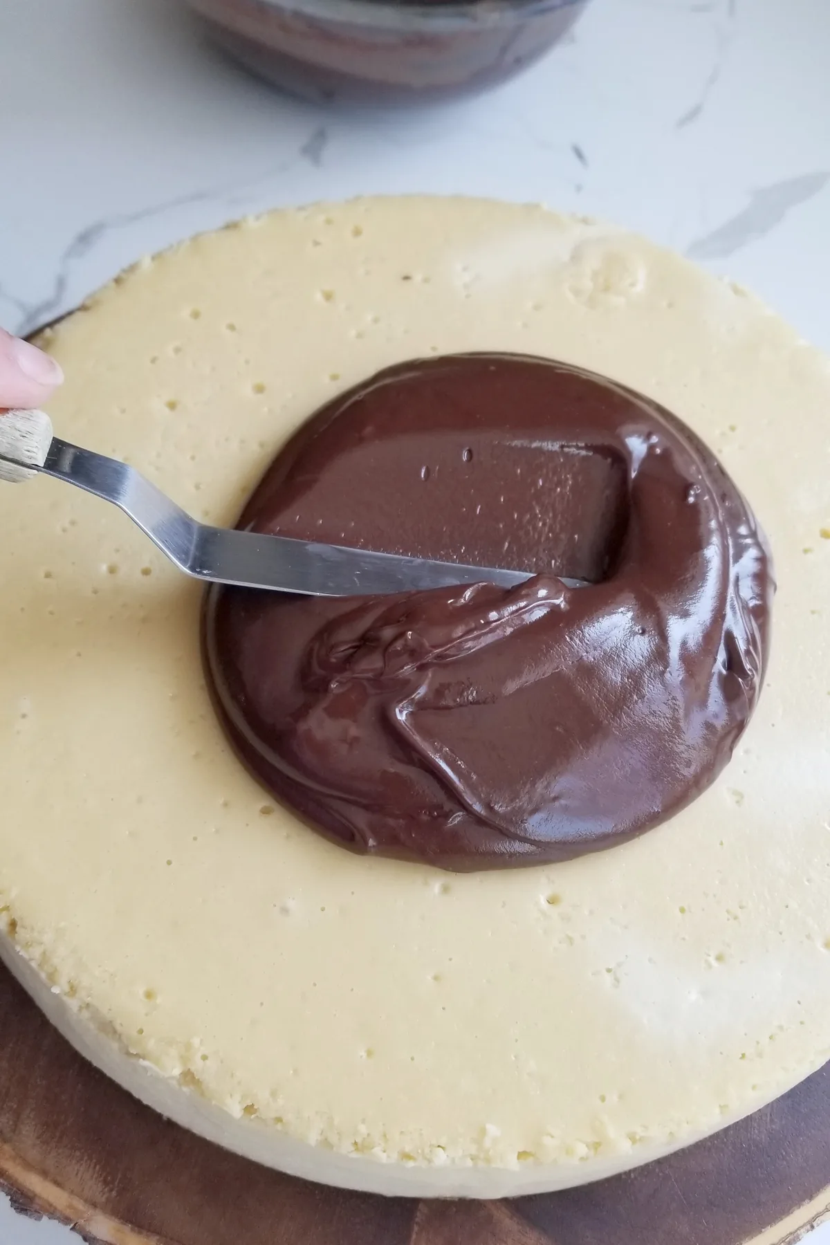 spreading ganache onto a cheesecake.