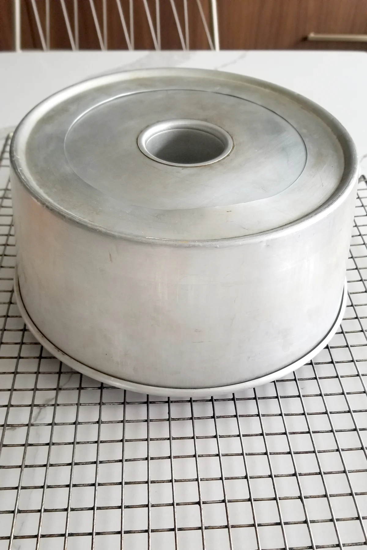 an angel food cake pan upside down on a cooling rack.