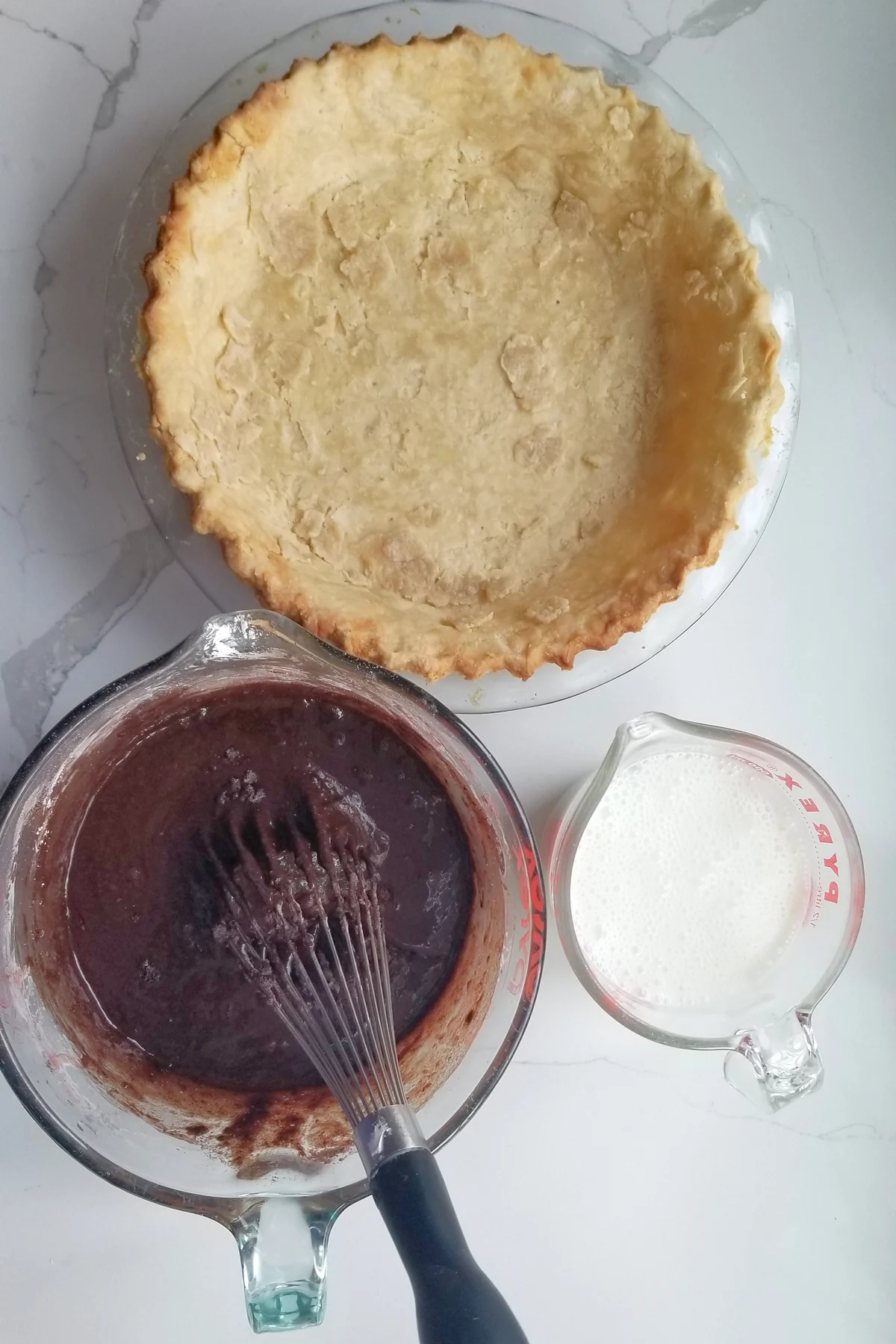 a pie shell, a bowl of chocolate and a cup of buttermilk