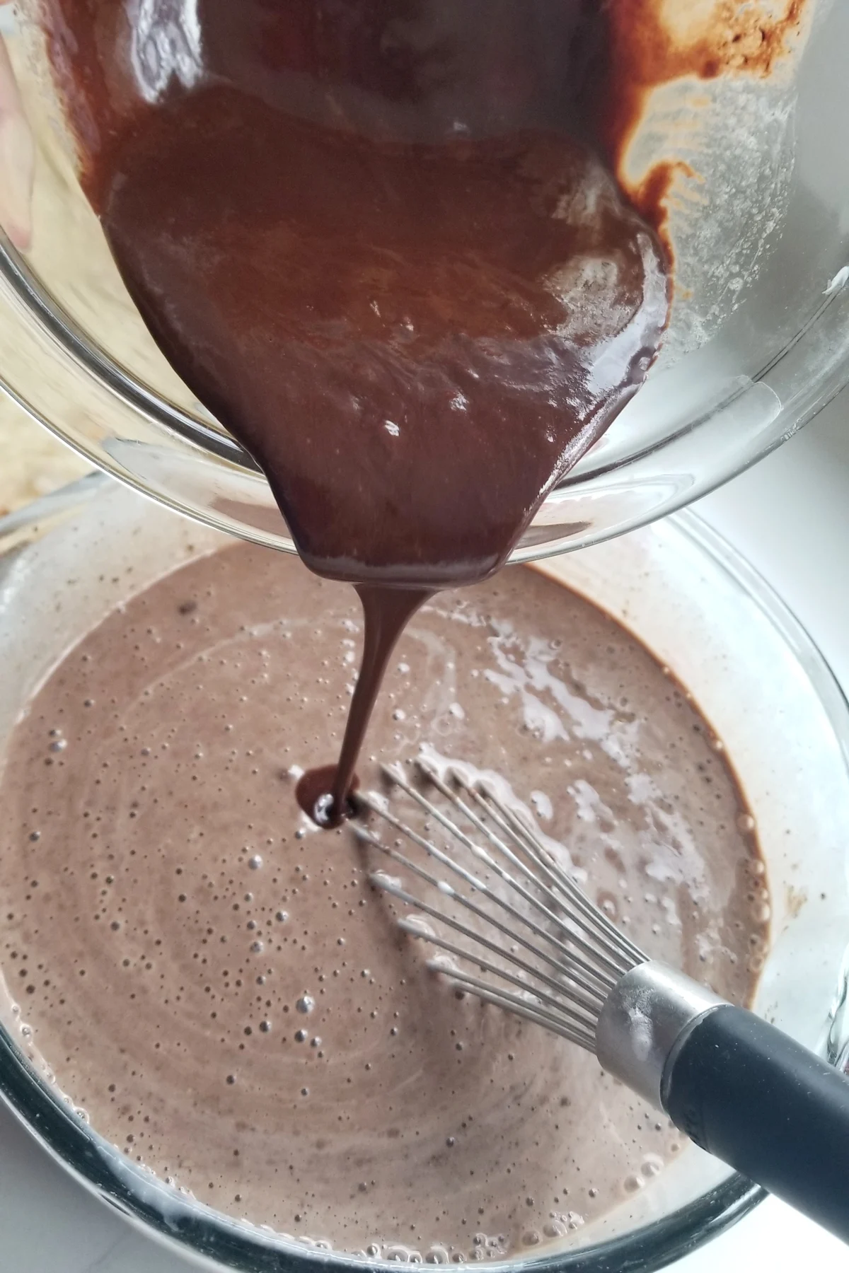 chocolate pouring into a bowl of chocolate batter.