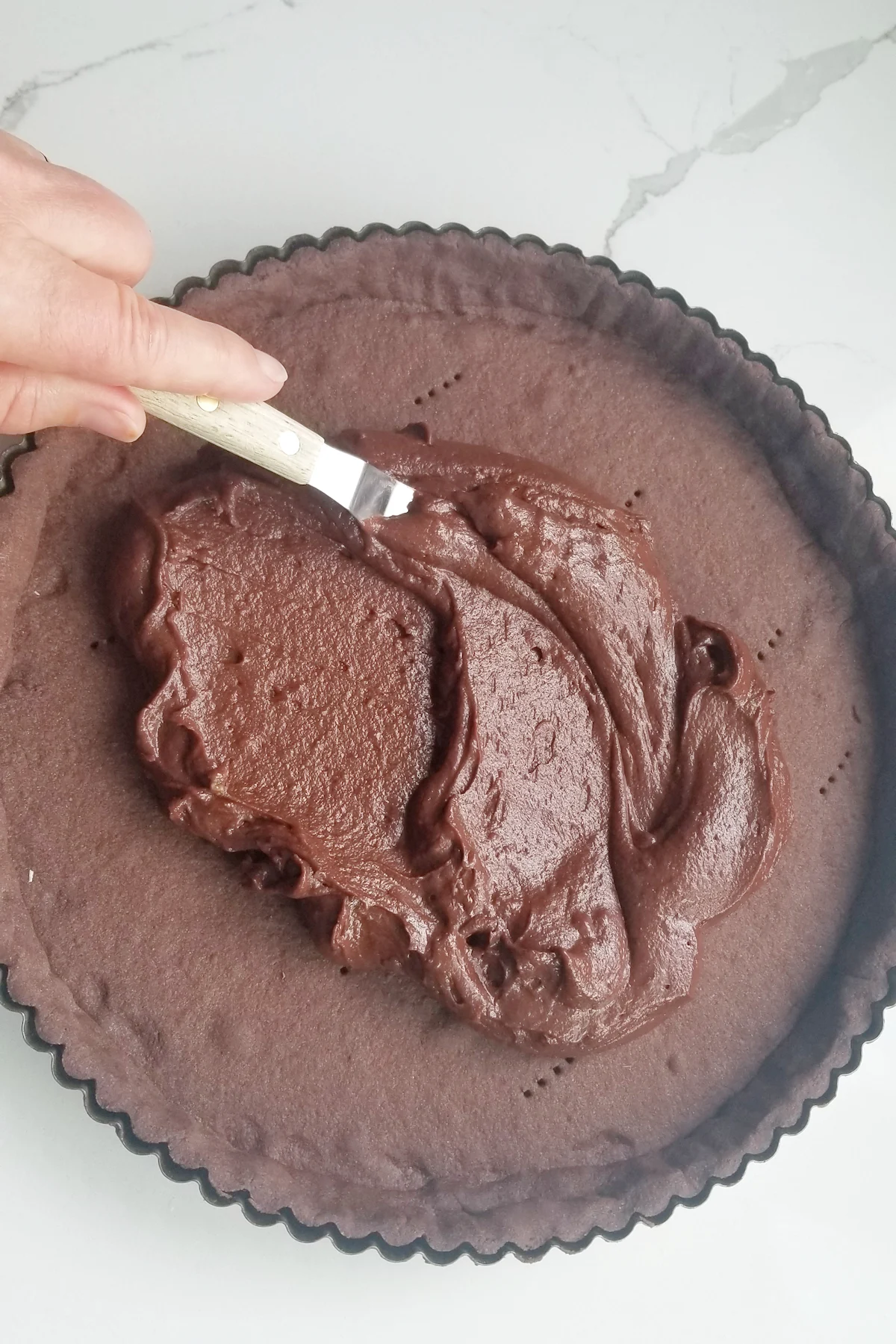 chocolate pastry cream being spread into a chocolate crust